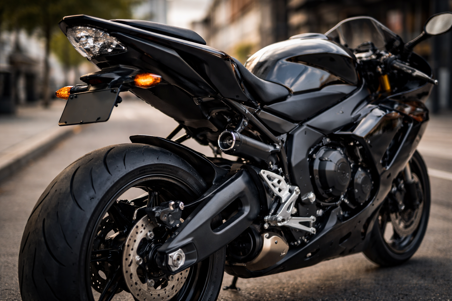 Sport motorcycle with rear tail tidy and frame sliders installed, parked on an urban street with focus on the rear section