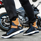 Person wearing navy and brown shoes with a motorcycle in the background
